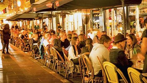 Rows of people eating food on Lygon street at night
