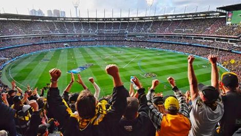 A crowd cheering at a game of AFL inside the Melbourne Cricket Ground